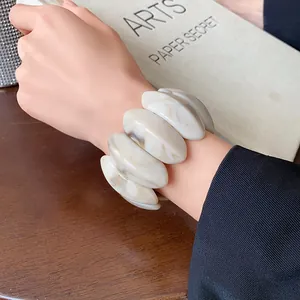 Detailed macro view of a chunky cream marble-textured oval elastic bracelet worn on a wrist