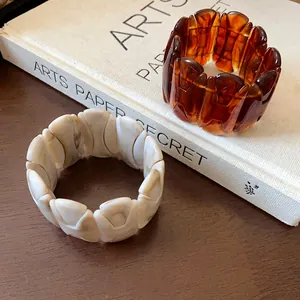 Detailed macro view of two vintage marbled elastic chunky bracelets displayed on an art book