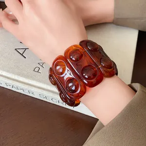 Detail of retro amber marbled resin bracelet with embossed circular patterns on wrist