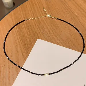 Minimalist black crystal beaded necklace with gold accents on a wooden background