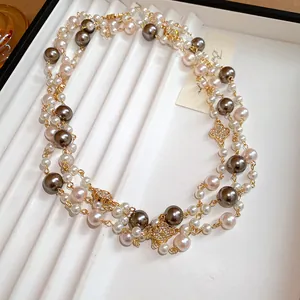 Dettaglio di una lunga collana di perle vintage con ciondoli a fiore e perle multicolori.