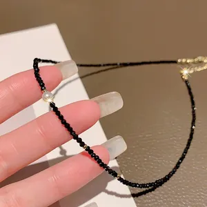 Elegant black faceted crystal necklace with pearl and gold accents shown in hand.