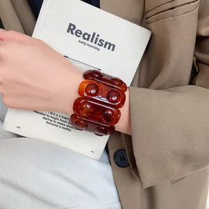 Close-up of a marbled amber resin elastic bracelet worn with a stylish blazer