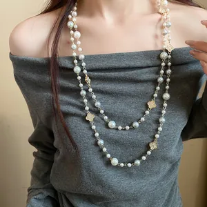 Elegante collana di perle a doppio strato con ciondoli a fiori su una modella