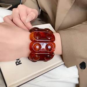 Close-up of a chunky amber retro acrylic elastic bracelet worn on a woman's wrist