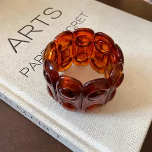 Vintage amber tortoiseshell elastic bracelet with oval links displayed on a beige book