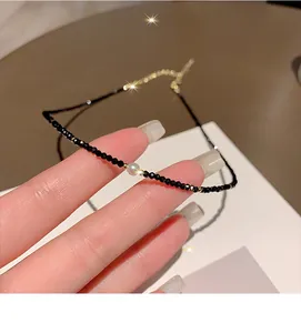 Detailed macro view of a minimalist black crystal necklace with a elegant pearl charm