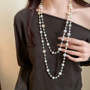 Elegante modella con una lunga collana di perle a doppio strato con fiori di strass