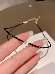 Detailed macro shot of a delicate black crystal choker necklace with a central white pearl