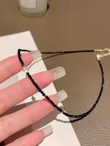 Detail view of an elegant black crystal beaded necklace with pearl and gold accents.
