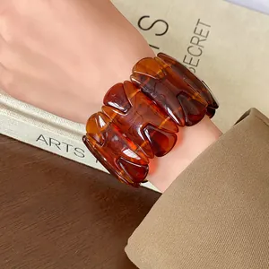 Detailed view of a vintage amber resin H-shaped elasticated bracelet on a woman's wrist