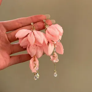 Dettaglio ravvicinato di orecchini a fiore in tessuto rosa con strass e perle di tendenza