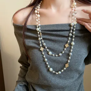 Dettaglio di una lunga collana di perle a due strati con pendenti a fiore