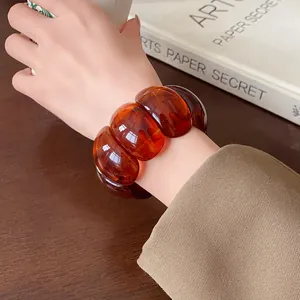 Close-up of a vintage amber oval segmented elastic bracelet worn on a female wrist