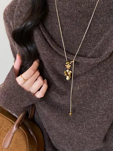 Primo piano di una collana vintage stile Maillard con resina e perle su maglione.