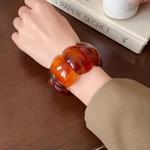Close-up of a vintage amber-colored resin oval stretch bracelet shown on a wrist