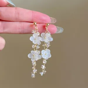 Detailansicht eleganter weißer Blumenohrringe mit Kristallperlen und Silberstiften