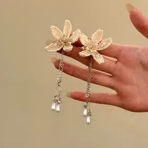 Dettaglio di orecchini a fiore di perline bianche con lunghe nappe e perle pendenti