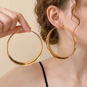 Übergroße goldene Creolen aus Metall, am Modell für einen minimalistischen Luxuslook.