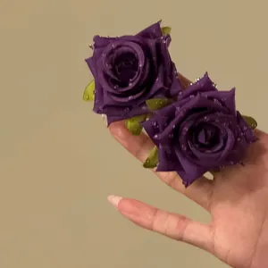 Primo piano dettagliato di orecchini a rosa in tessuto viola con gocce di rugiada in perline