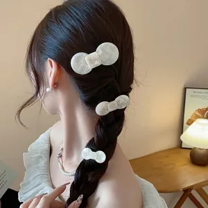 Set of three elegant white resin hair clips displayed on a stylishly braided hairstyle