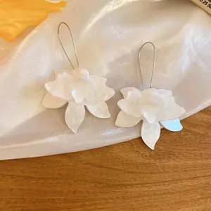 Dettaglio macro di eleganti orecchini a fiore in tessuto bianco con ganci in argento