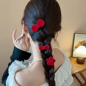 Close-up of red resin flower and bow hair clips styled in a braided hairstyle.