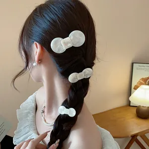 Detailed view of white marble resin bow hair clips elegantly styled on a braided hairstyle