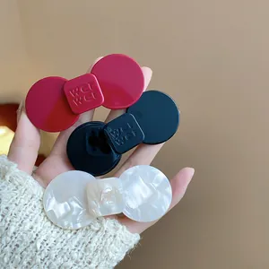 Close-up of three minimalist resin hair clips in red, black, and pearl white colors.