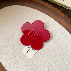 Detailed view of a vibrant red resin flower hair clip with embossed square center detail