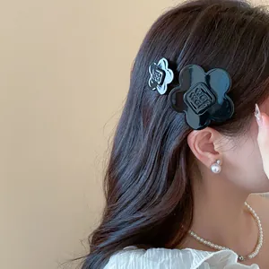 Macro view showing a pair of black resin flower hair clips on model's wavy hair
