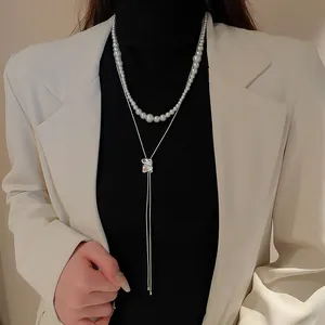 Collier lariat élégant à deux rangs en perles et argent sur col roulé noir et blazer.