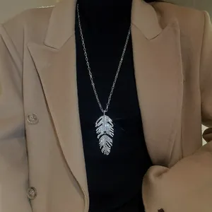 Gros plan d'un collier sautoir élégant avec pendentif plume serti d'oxydes de zirconium.