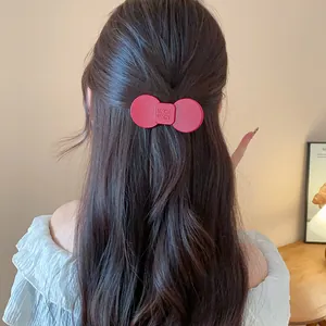 Detail shot of a woman with long wavy hair styled with a red resin bow hair clip accessory