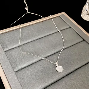 Minimalist silver necklace with a circular translucent resin pendant on a display box