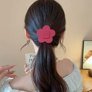 Detailed view of a red resin flower hair clip styled in a classic messy ponytail.