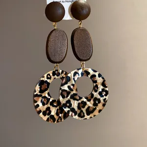 Macro close-up detail showing the texture of leopard print and dark wood circular drop earrings