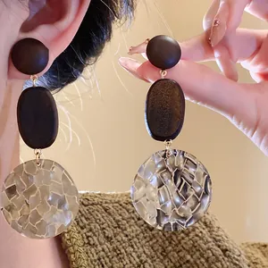 Detailed macro view of elegant wood and mosaic pattern resin drop earrings for women.