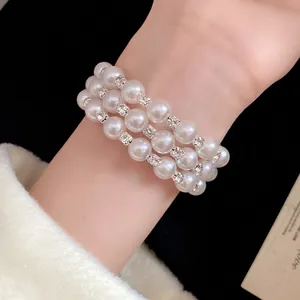 Detail view of an elegant three-layer pearl bracelet with sparkly rhinestone spacers.