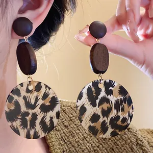 Detail view of large wooden leopard print round drop earrings on model