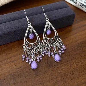 Close-up of bohemian silver-tone earrings featuring purple waterdrop stones and tassel details