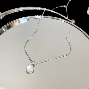 Detailed close-up of minimalist round resin pendant necklace on a reflective mirror