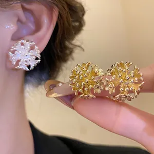 Macro view of 18k gold plated flower cluster earrings shown in gold and silver tones