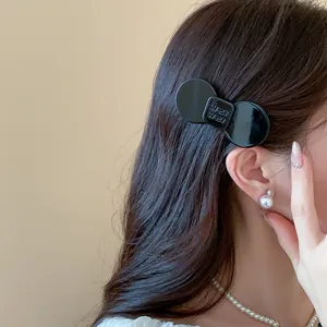Detailed shot of a minimalist black resin bow hair clip styled in a woman's hair