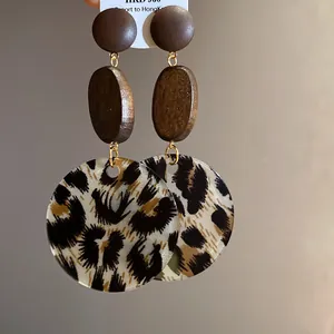 Close-up of wooden drop earrings with leopard print circular pendants