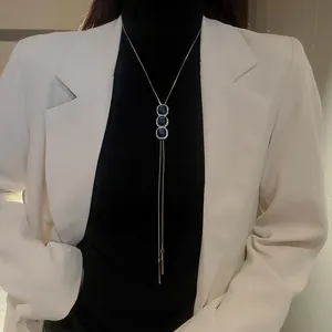 Détail d'un collier long élégant avec trois zircons bleus carrés sur un modèle