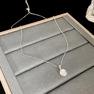 Detailed view of a minimalist silver chain necklace with a round white resin pendant