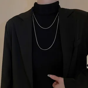 Vue détaillée d'un collier chaîne serpent argenté à double épaisseur sur une tenue noire.
