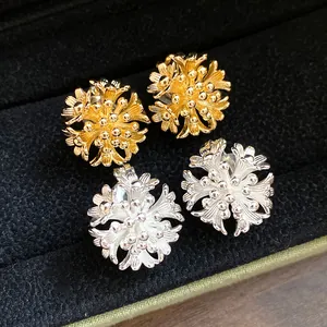 Close-up of 18k gold and silver plated floral cluster clip-on earrings in jewelry box.