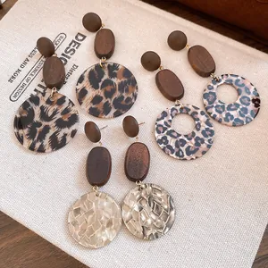 Detailed macro shot of various wood dangle earrings featuring leopard and pearlescent textures
